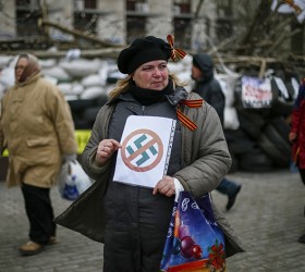 A pro-Russia protester holds an anti-swastika sign in front of a barricade outside a regional government building in Donetsk