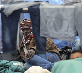 A migrant from Sudan rests in the courtyard at a food distribution centre after he fled a makeshift camp to find shelter in Calais