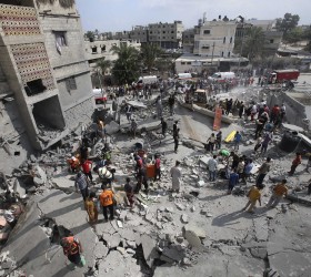 Palestinian rescue workers search for victims as people gather atop the remains of a house in Khan Younis in the southern Gaza Strip