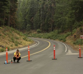 A Yosemite National Park employee squats near barriers on the closed Highway 120 in Big Oak Flat