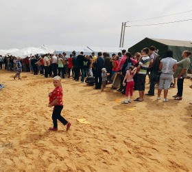 People stand in a line to enter a canteen and have dinner at a temporary tent camp set up for Ukrainian refugees outside Donetsk