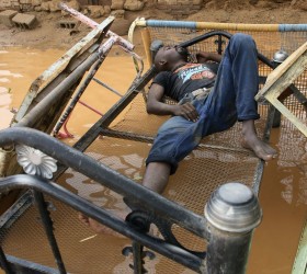 A man takes a nap in front of a home damaged by flood waters in Salhaa, Omdurman
