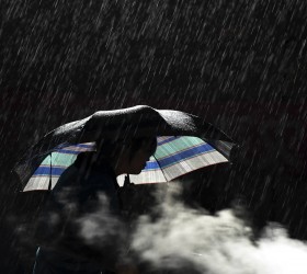 A woman holds an umbrella as she cooks in the rain at the earthquake zone of Longtoushan town