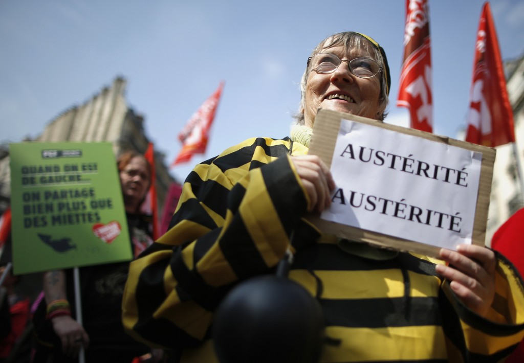 A protester dressed as a prisoner marches through the streets of Paris during a demonstration against austerity plans