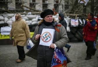 A pro-Russia protester holds an anti-swastika sign in front of a barricade outside a regional government building in Donetsk