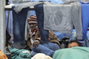 A migrant from Sudan rests in the courtyard at a food distribution centre after he fled a makeshift camp to find shelter in Calais