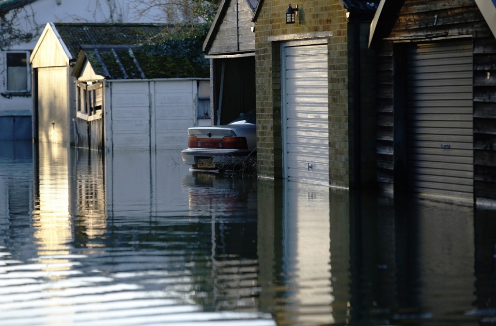 The boot of a car protrudes from a flooded row of garages after the river Thames flooded the village of Wraysbury