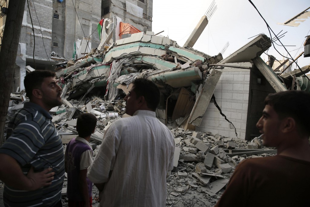 Palestinians stand by the rubble of the home of Hamas Gaza leader Ismail Haniyeh in Gaza City