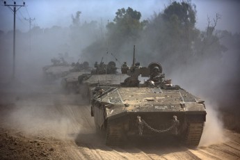 Israeli APCs drive near the Israeli border with Gaza as the come out of the Gaza Strip