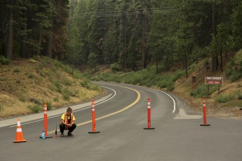 A Yosemite National Park employee squats near barriers on the closed Highway 120 in Big Oak Flat
