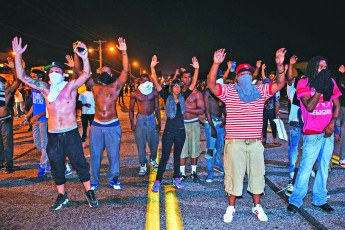 Διαδηλωτές στο Φέργκιουσον σηκώνουν ψηλά τα χέρια, μπροστά στη θέα των ένοπλων στρατιωτών που κατέβασε στο δρόμο η Πολιτεία του Μιζούρι