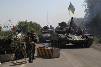 Ukrainian army tanks move past a checkpoint as they patrol area near eastern Ukrainian town of Debaltseve