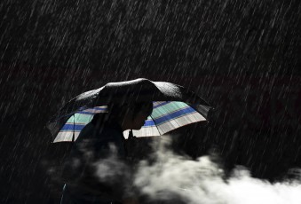 A woman holds an umbrella as she cooks in the rain at the earthquake zone of Longtoushan town