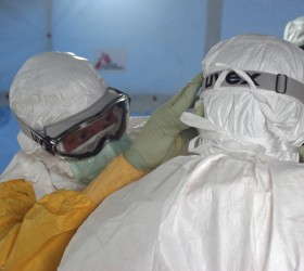 Dr. Joel Montgomery, team leader for the U.S. Centers for Disease Control and Prevention Ebola Response Team in Liberia, is dressed in his personal protective equipment while adjusting a colleague's PPE before entering the Ebola treatment