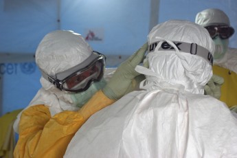 Dr. Joel Montgomery, team leader for the U.S. Centers for Disease Control and Prevention Ebola Response Team in Liberia, is dressed in his personal protective equipment while adjusting a colleague's PPE before entering the Ebola treatment
