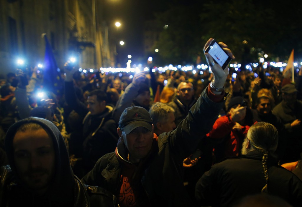 People hold up their mobile phones as they protest against a new tax on Internet data transfers in the centre of Budapest